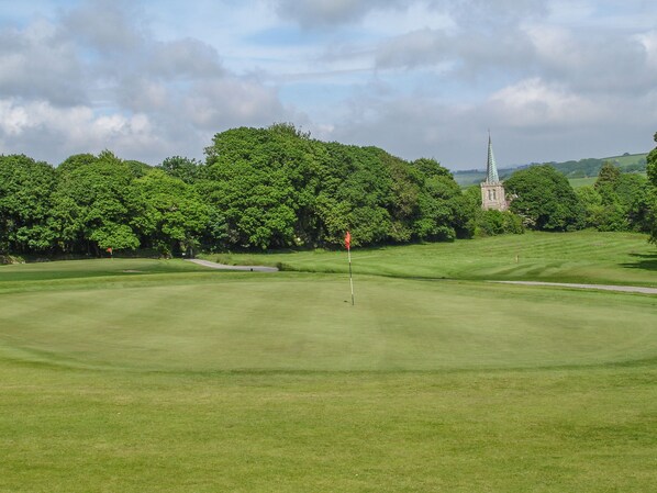 A golf course with a church in the background. - Birch (Truro)
