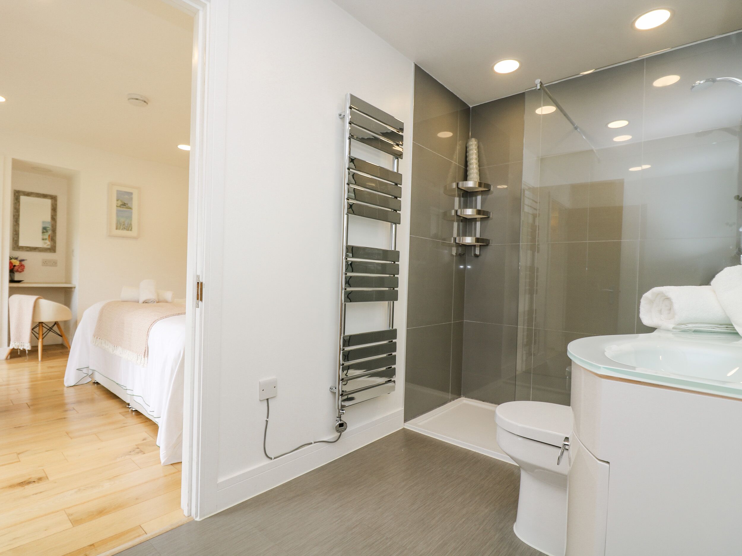 A modern bathroom with a glass shower enclosure, a toilet, and a built-in towel rack.