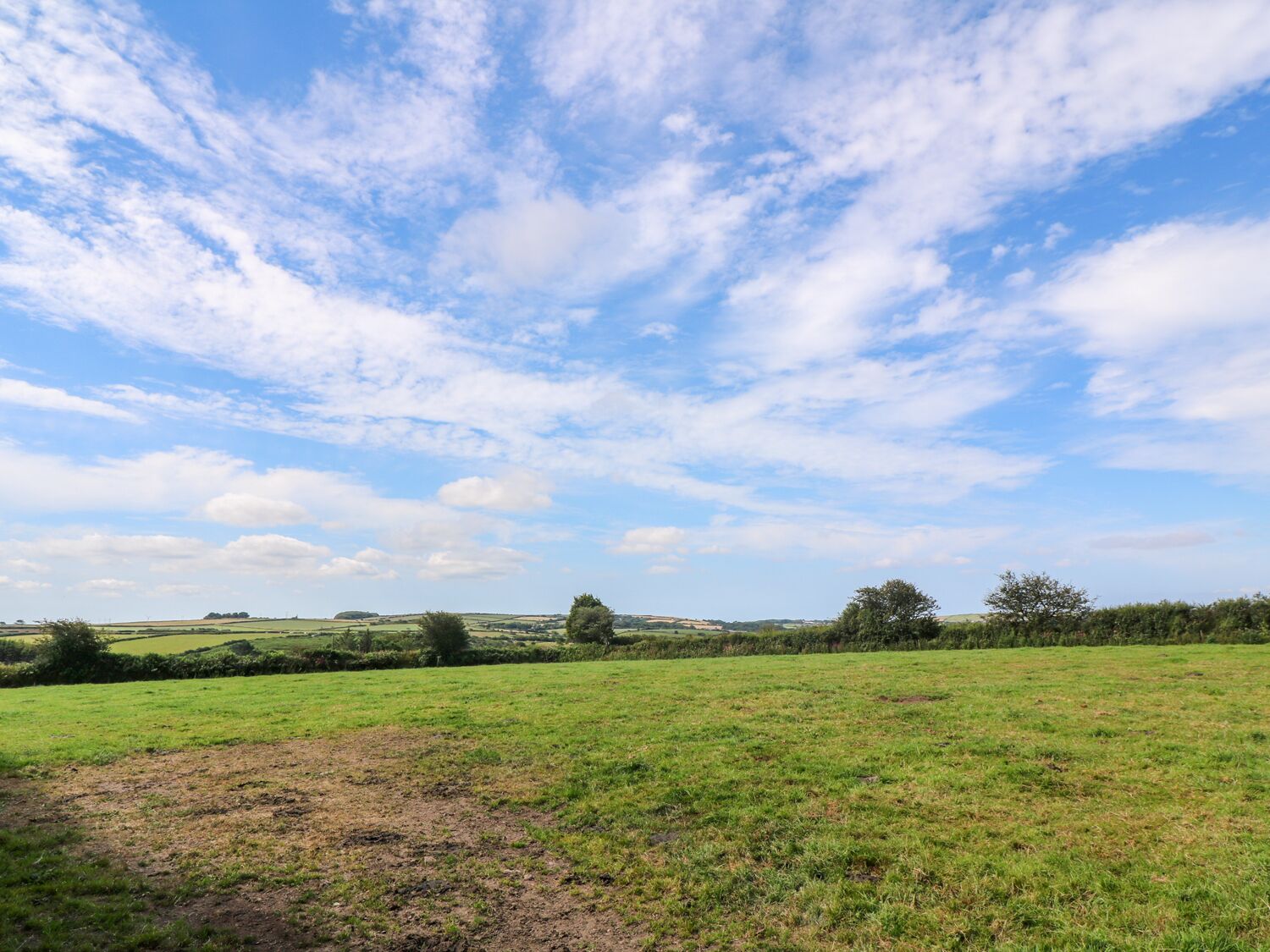 Un campo extenso con cielo despejado y nubes dispersas.