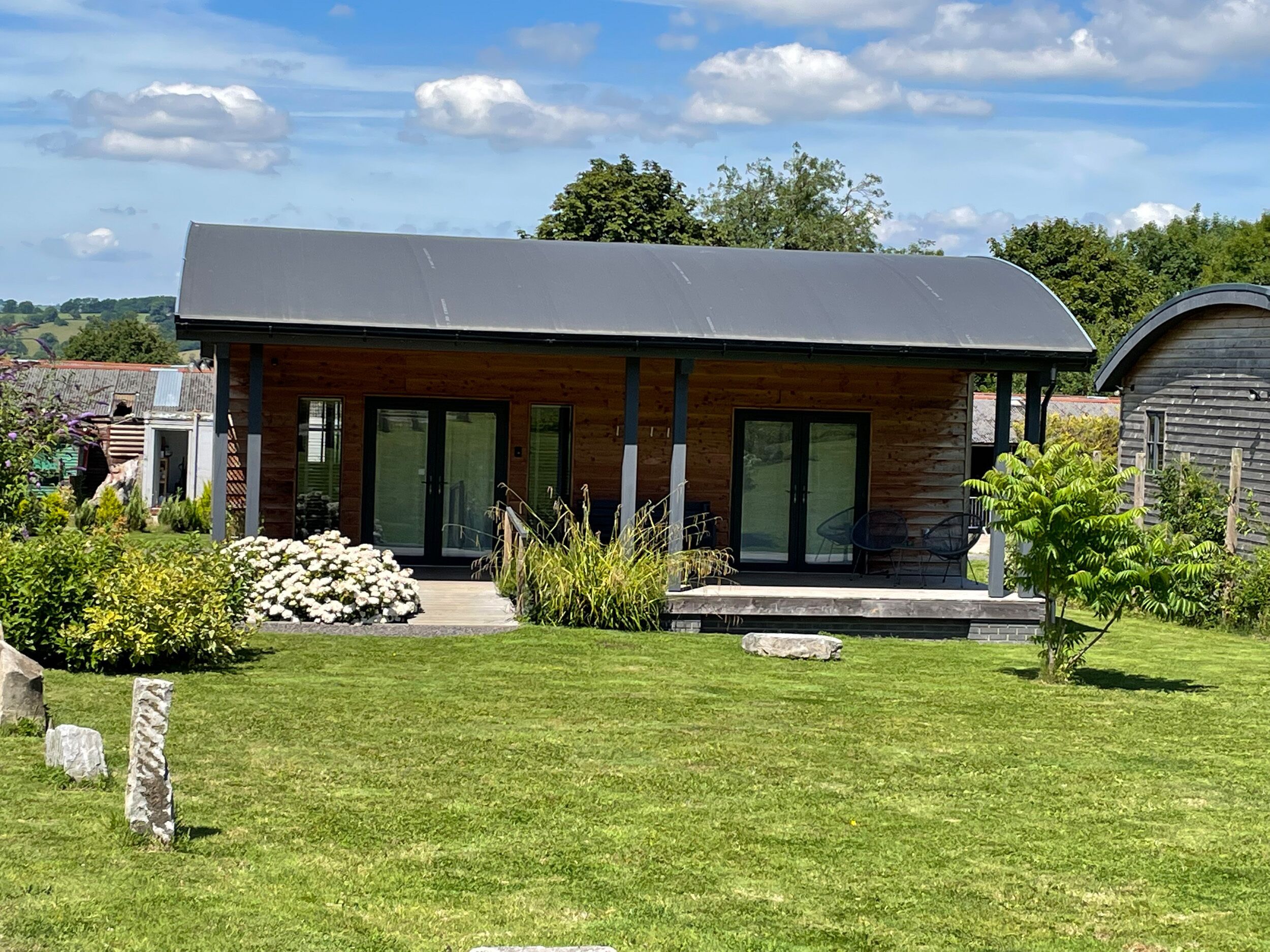 Une maison moderne avec un toit plat, de grandes portes vitrées et une pelouse bien entretenue.