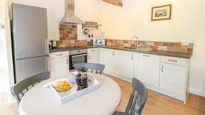 A modern kitchen with white cabinets, a stainless steel refrigerator, a microwave, and a coffee maker on the counter. - The Granary (Dereham)