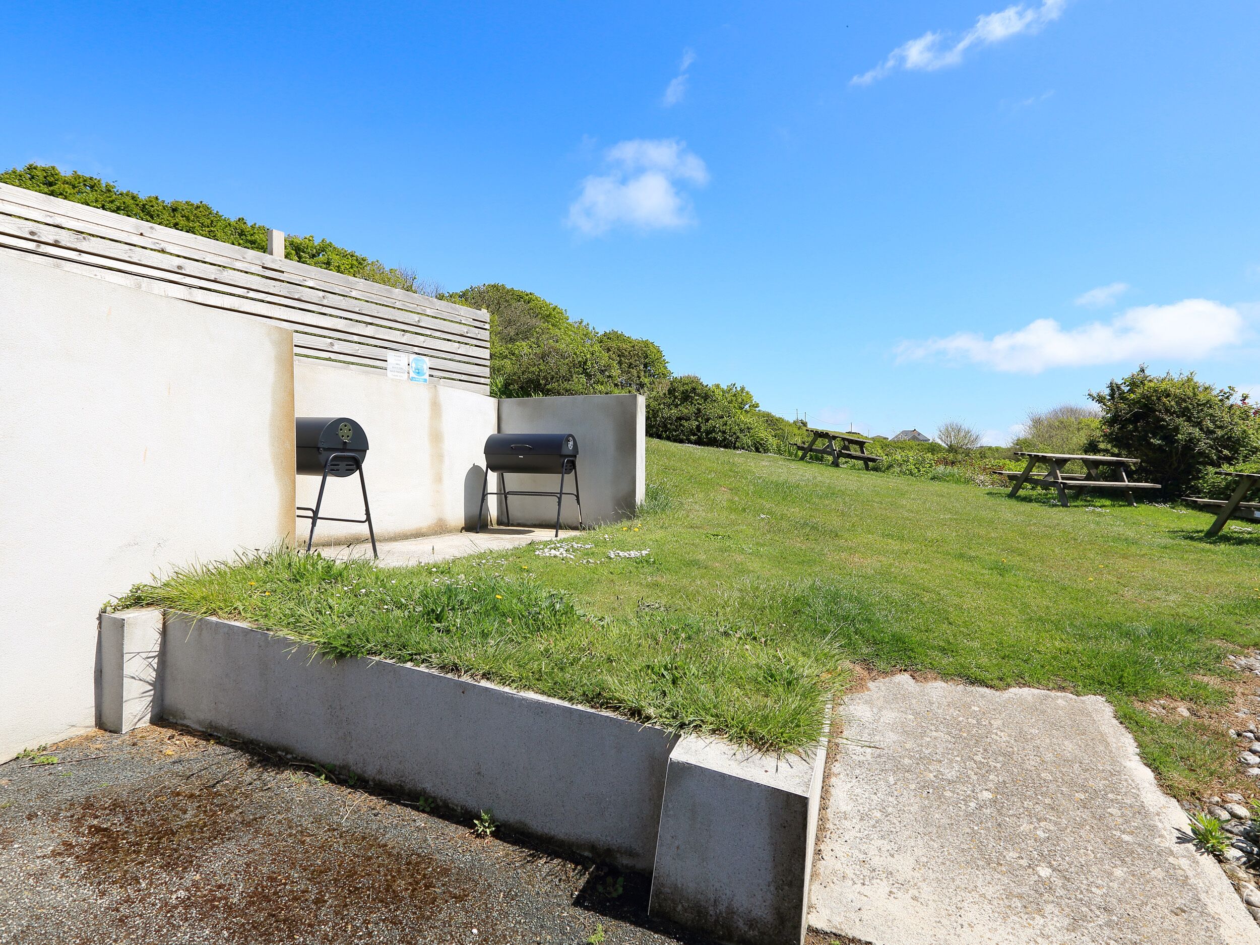 A grassy outdoor area with a barbecue grill and a picnic table.