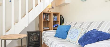 A bedroom with a bed, a small table, a bookshelf, and a staircase.