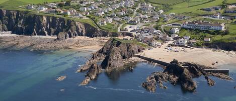 A coastal town with a rocky shoreline, houses, and a clear view of the surrounding countryside.