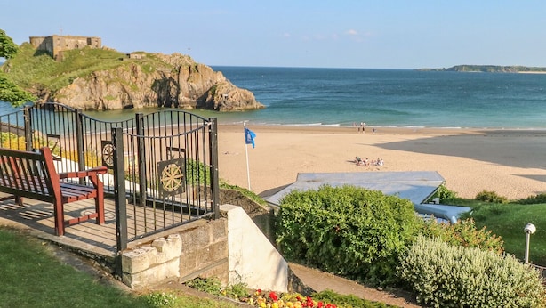 Une vue côtière comprenant une plage, un bâtiment historique et une porte dotée d’une roue.