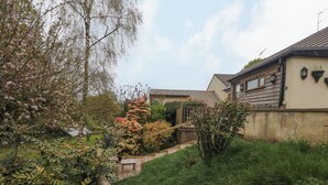 A residential area with a wooden fence, a garden with various plants, and a house with a tiled roof.