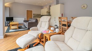 A modern living room with a sofa, armchairs, a coffee table, and a television. - Coal Drops (Alnwick)