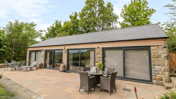 A modern house with a patio area featuring outdoor furniture and a stone fireplace. - Coal Drops (Alnwick)