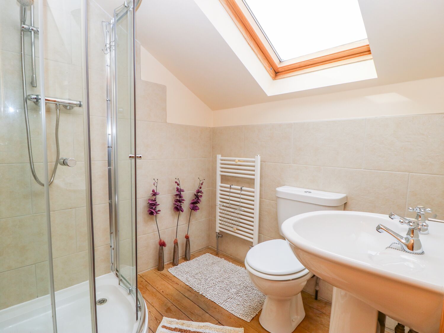 A modern bathroom with a glass-enclosed shower, a white toilet, and a sink with a mirror.