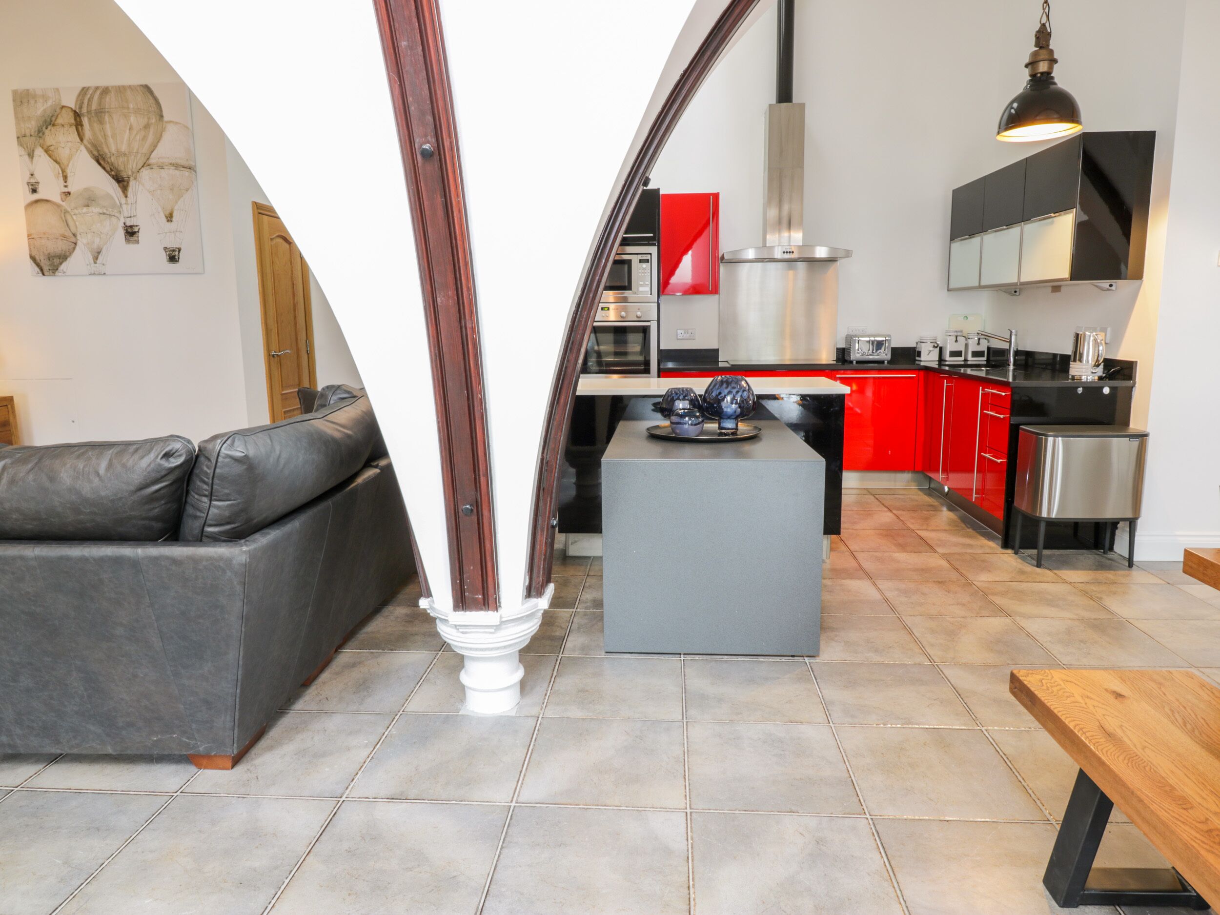 Een moderne keuken met rode kastjes, een grijs kookeiland en een zwart aanrecht.