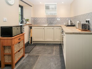 A compact kitchen with a microwave, toaster, and sink. - Stable Cottage (Berwick-upon-Tweed)