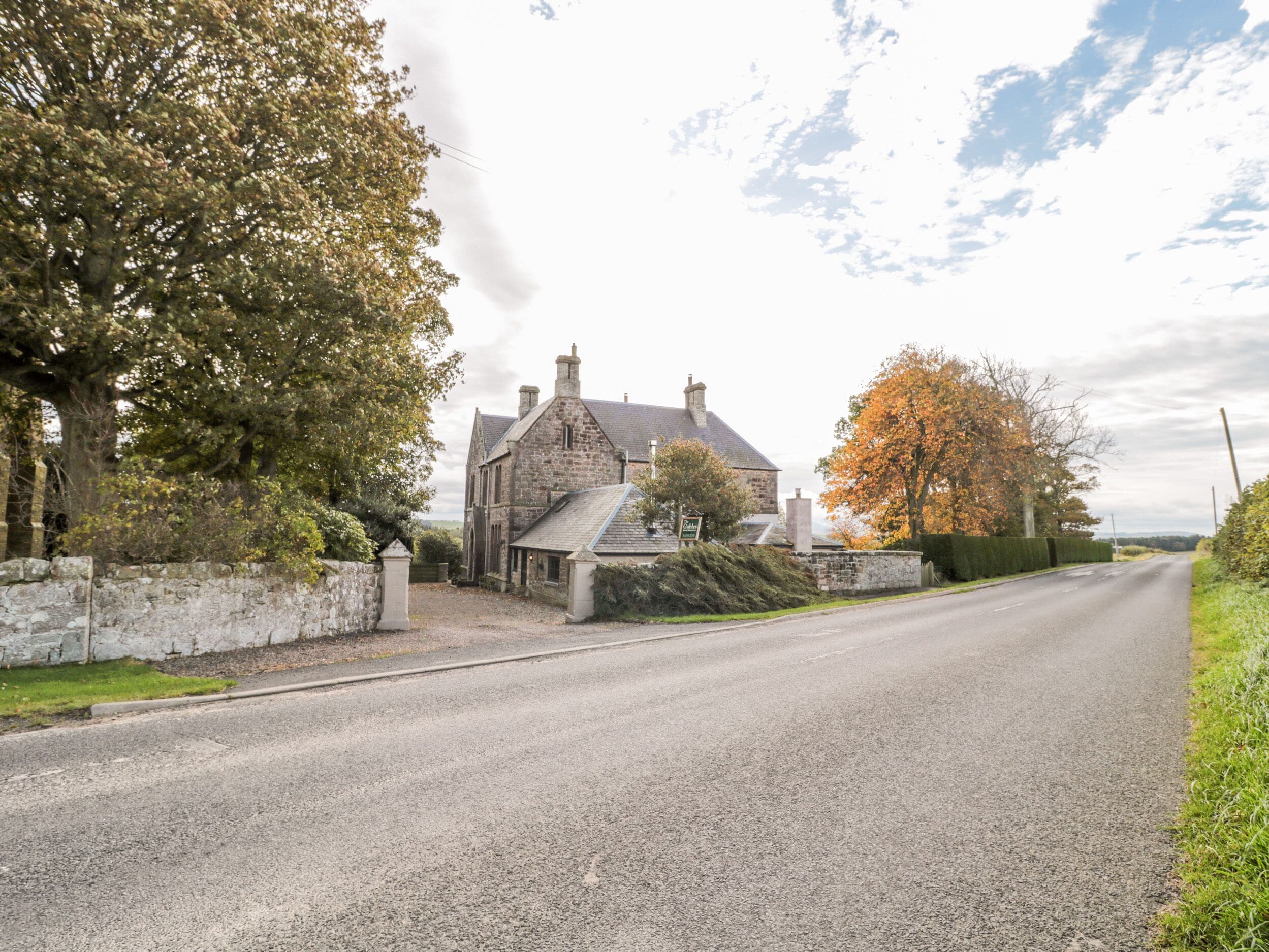 A stone building with a sign reading "Cottage" on a rural road.