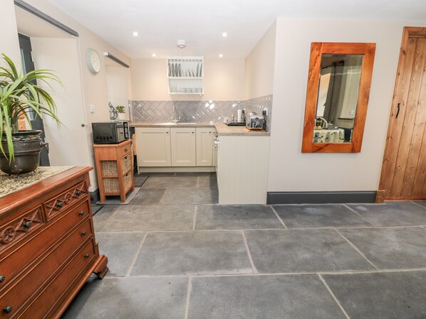 Een moderne keuken met een centraal eiland, een houten kast, een potplant en een klok aan de muur.