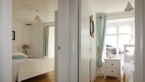Un dormitorio con cama, mesitas de noche, lámpara, ventana con cortinas y vistas a la ciudad.