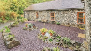 A stone building with a gravel driveway and potted plants. - Felin Iago (Aberystwyth)