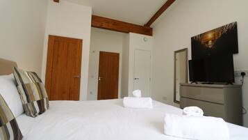 A hotel room with a bed, two wooden doors, a television, and a dresser.