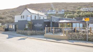 Un edificio costero con un cartel que dice 'The Unicorn On The Beach' y un letrero de 'Welcome' sobre la entrada.