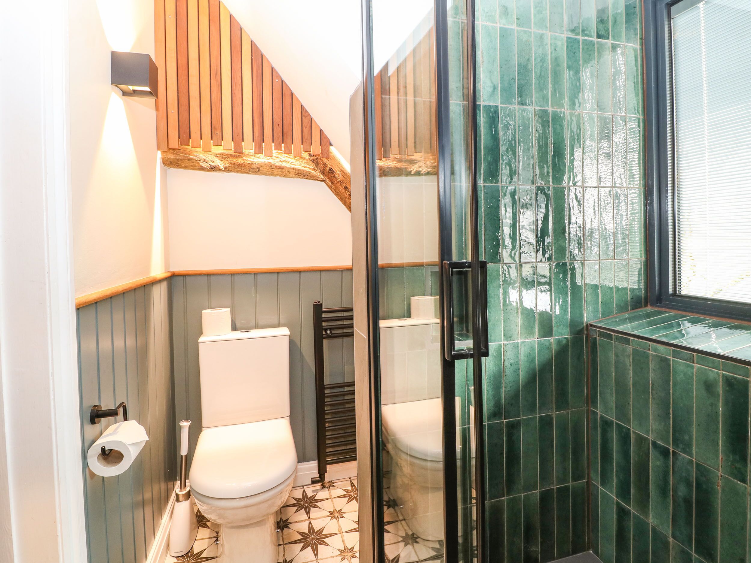 Un baño con dos inodoros, una zona de ducha y una ventana.