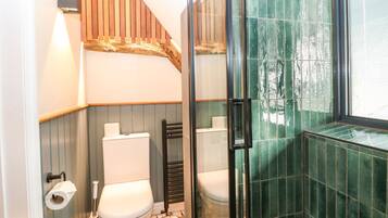 Un baño con dos inodoros, una zona de ducha y una ventana.