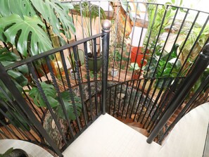 Stunning spiral staircase surrounded by lush foliage and potted plants, leading to an upper level.
