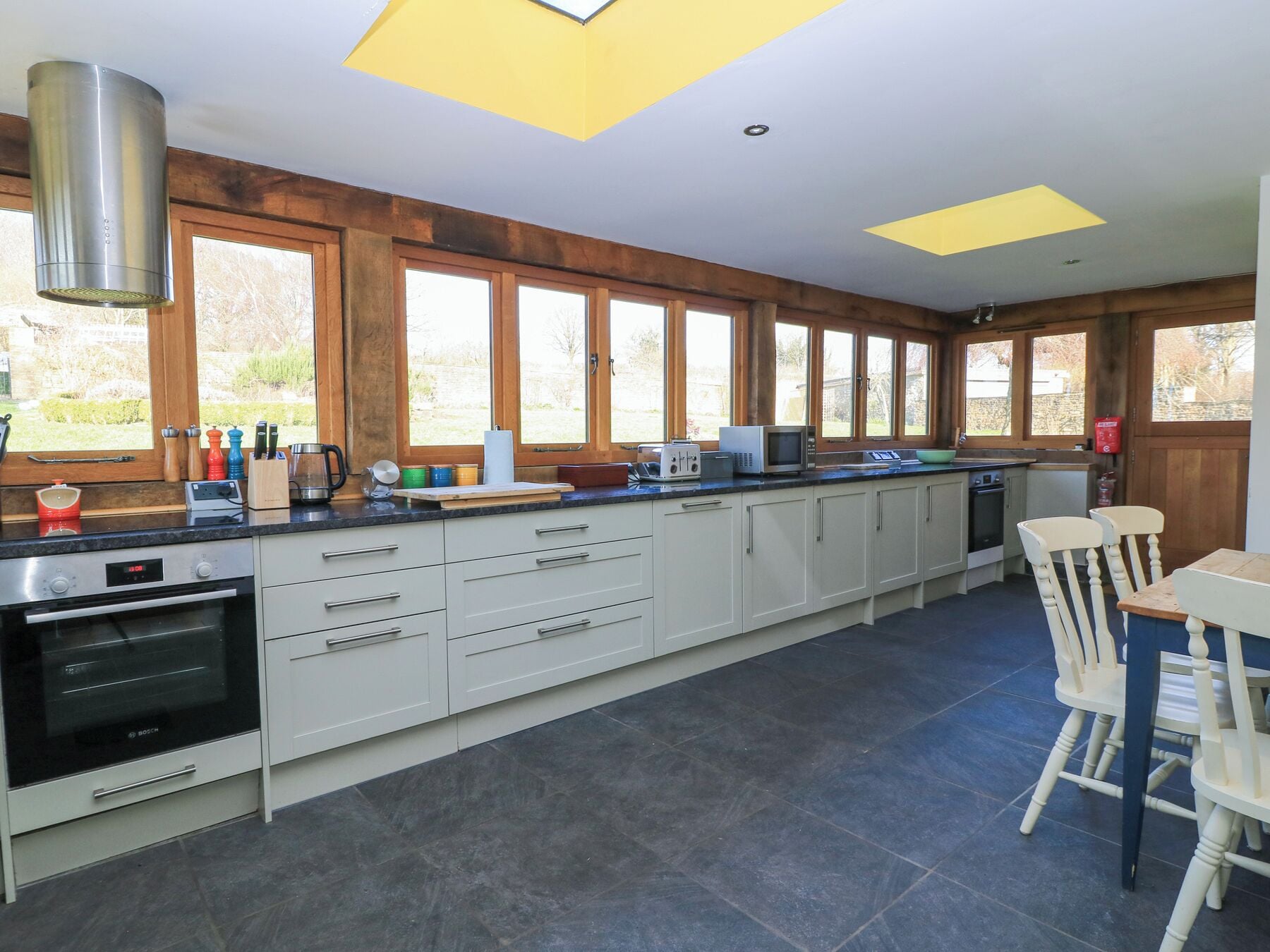 A modern kitchen with a large island, built-in appliances, and large windows.