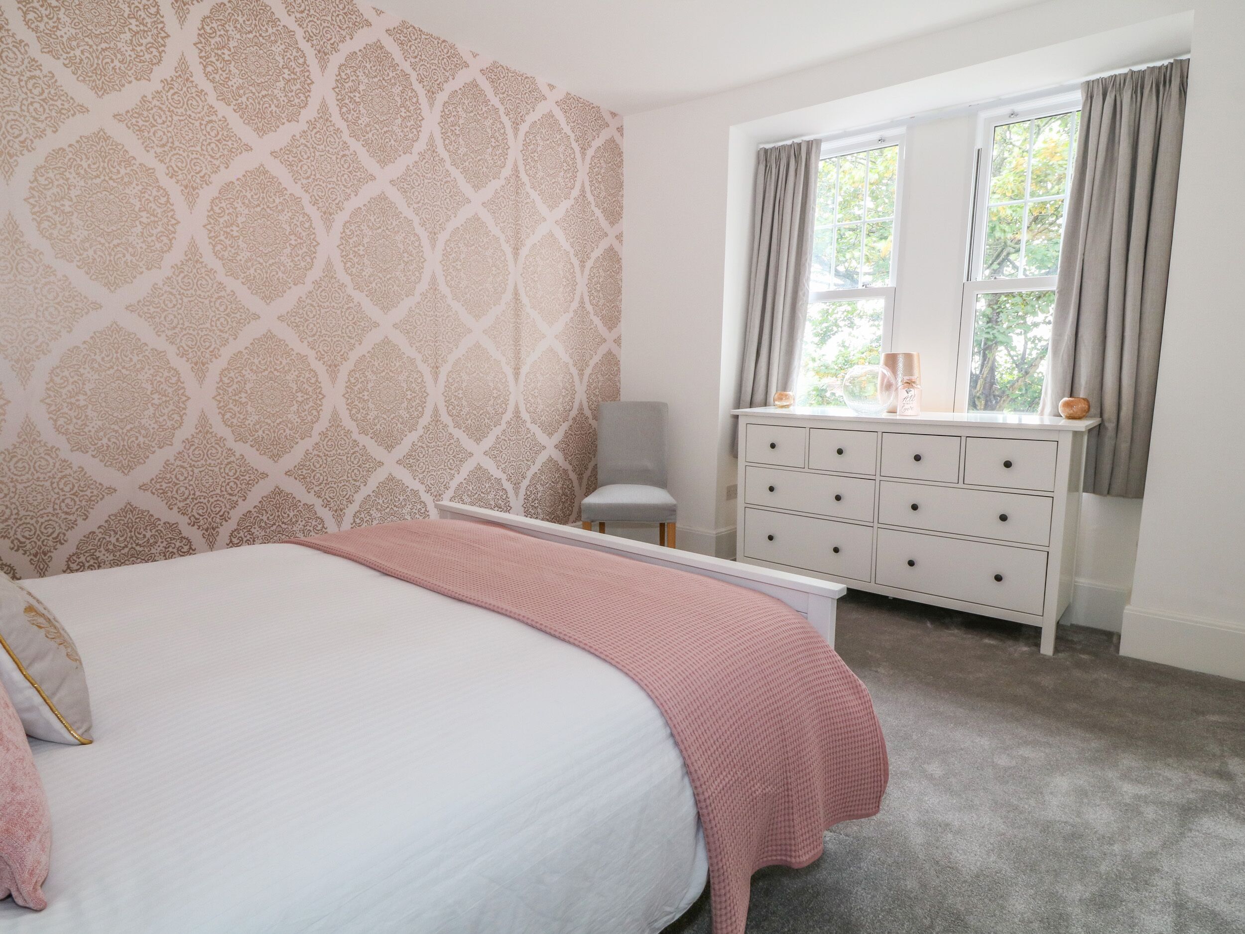Une chambre à coucher avec un lit, une commode et une fenêtre avec des rideaux.