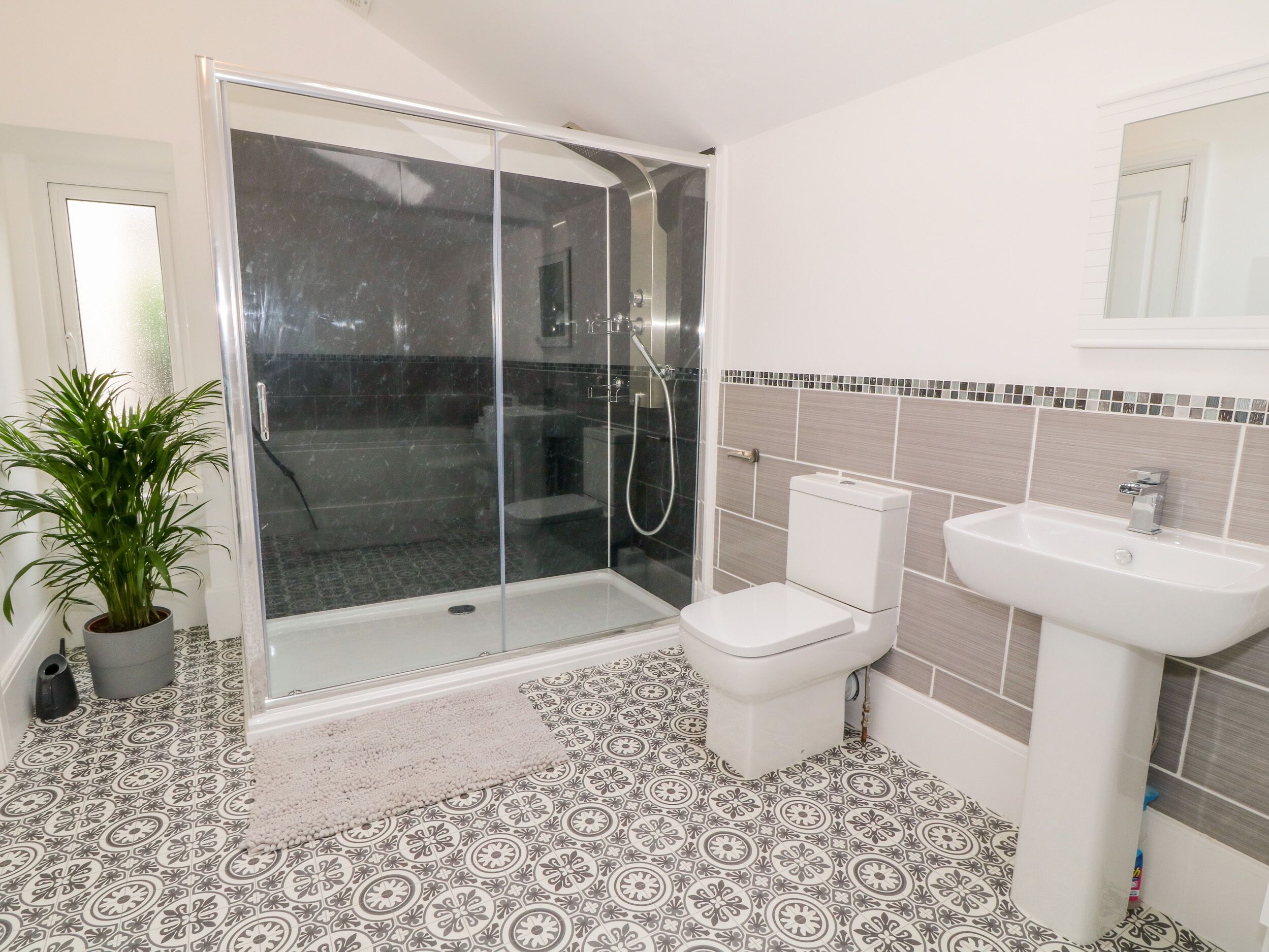 Une salle de bain équipée d’une douche, de toilettes, d’un lavabo et d’une plante en pot.