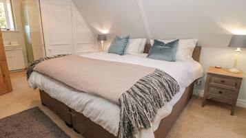 A bedroom with a large bed, two bedside tables, a nightstand, a window, and a door.
