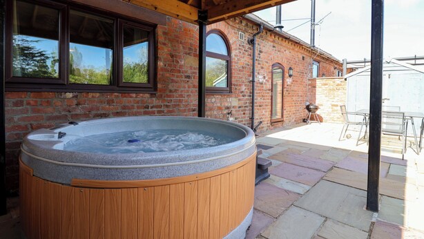Ein Whirlpool unter einer Holz-Pergola, Ziegelmauern und eine Steinterrasse.