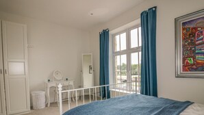 A bedroom with a bed, a desk, a chair, a wardrobe, and a window with curtains. - Cherrywood Manor (Bodmin)