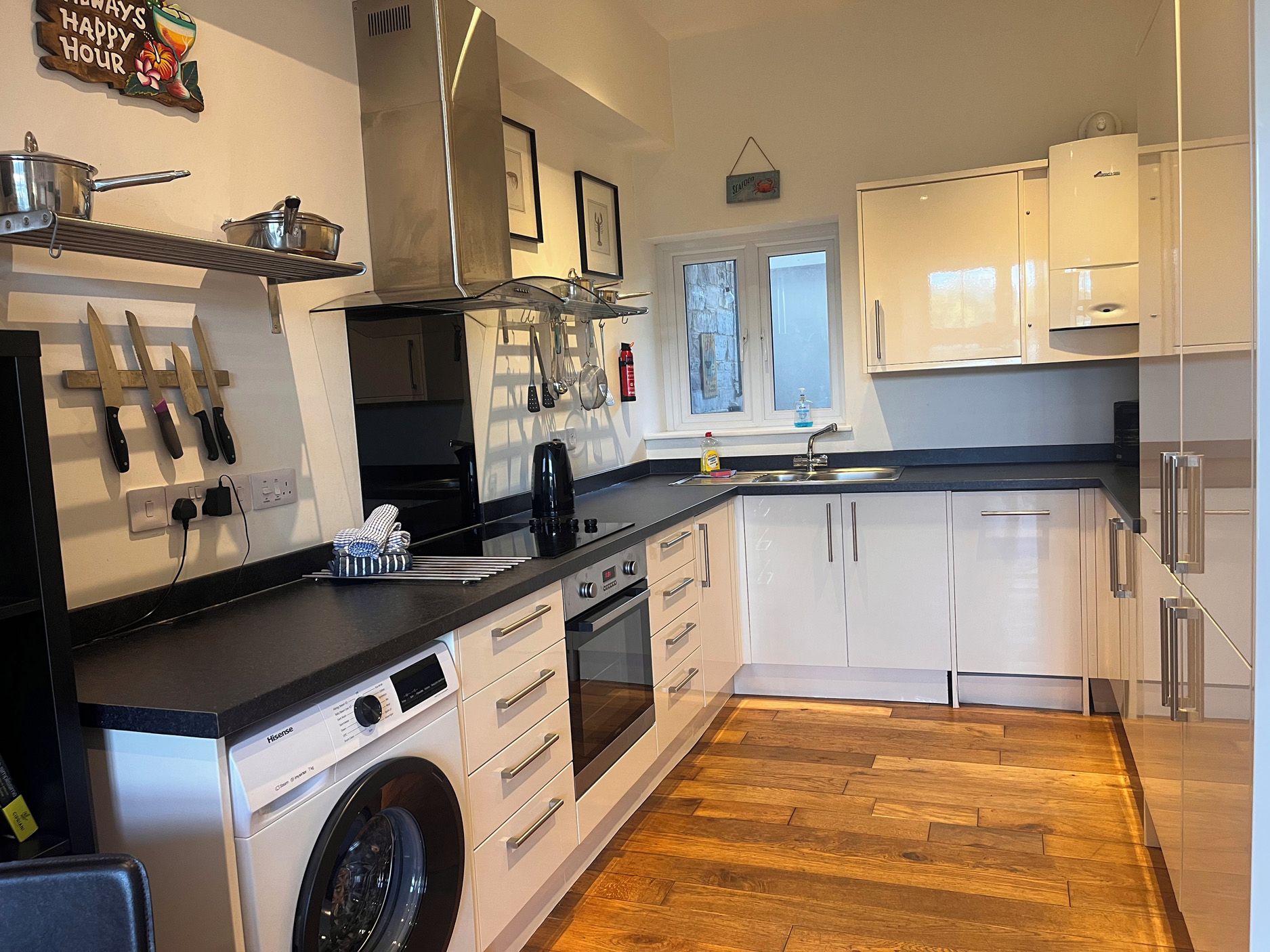 A modern kitchen with white cabinetry, a built-in oven, a washing machine, and a coffee maker.
