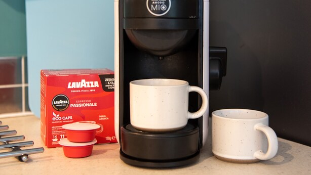 A coffee maker with a box labeled "Lavazza" and two coffee cups on a countertop. - Yr Adfa (Blaenau Ffestiniog)