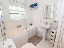 Un baño con ducha de vidrio, lavabo blanco y retrete.