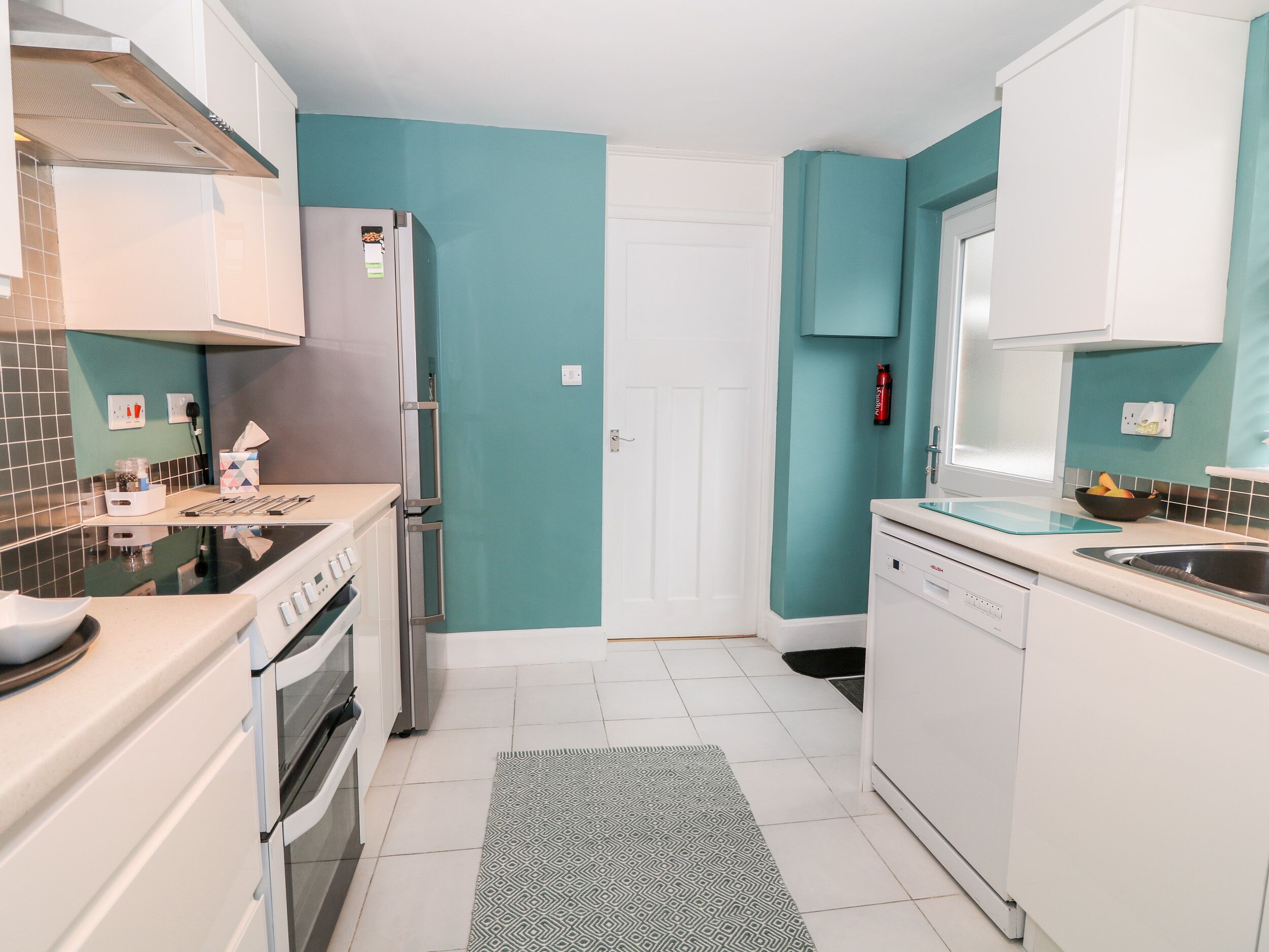 Une cuisine moderne avec des murs de couleur turquoise, des armoires blanches, un réfrigérateur en acier inoxydable et un lave-vaisselle.
