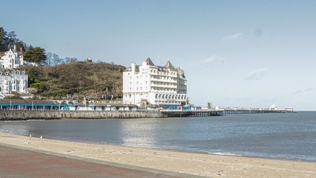 Ein Küstenhotel mit einem markanten Gebäude und einem Steg, der sich ins Wasser erstreckt.