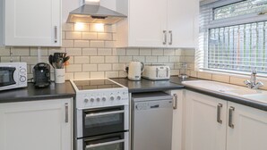 Eine moderne Küche mit weißen Schränken, einem Einbauofen, einem Geschirrspüler, einer Mikrowelle und einem Toaster.