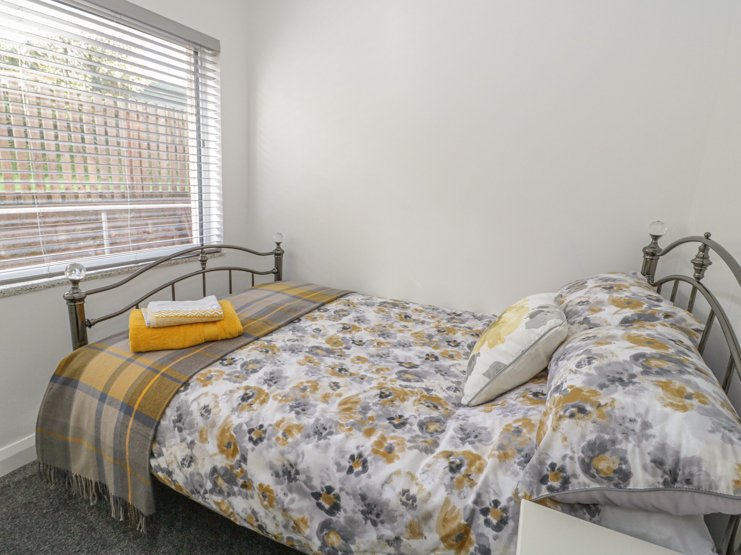 Una camera da letto con un letto, una finestra con persiane e vista sull'esterno.