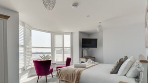 Une chambre moderne avec un grand lit, un bureau, une chaise et un téléviseur.