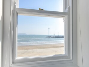 A window with a view of a beach and a pier. - High Tide (Weymouth)