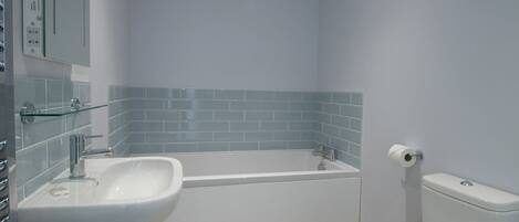 Et badeværelse med en hvid vask, badekar og toilet.