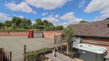 Un espace patio avec un jacuzzi, une table en bois et une cabine téléphonique rouge.