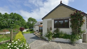 A quaint house with a gravel driveway, a wooden fence, and a sign indicating a parking area. - Valley View (Helston)
