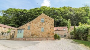 Un bâtiment en pierre avec un toit en pente, une allée gravillonnée et une porte verte.