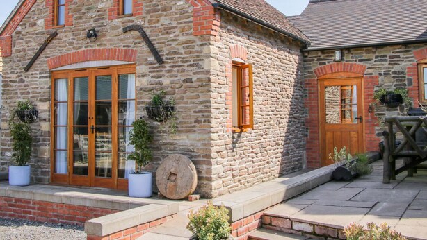 A stone building with a pitched roof, wooden doors, and windows. - High Grove (Ludlow)