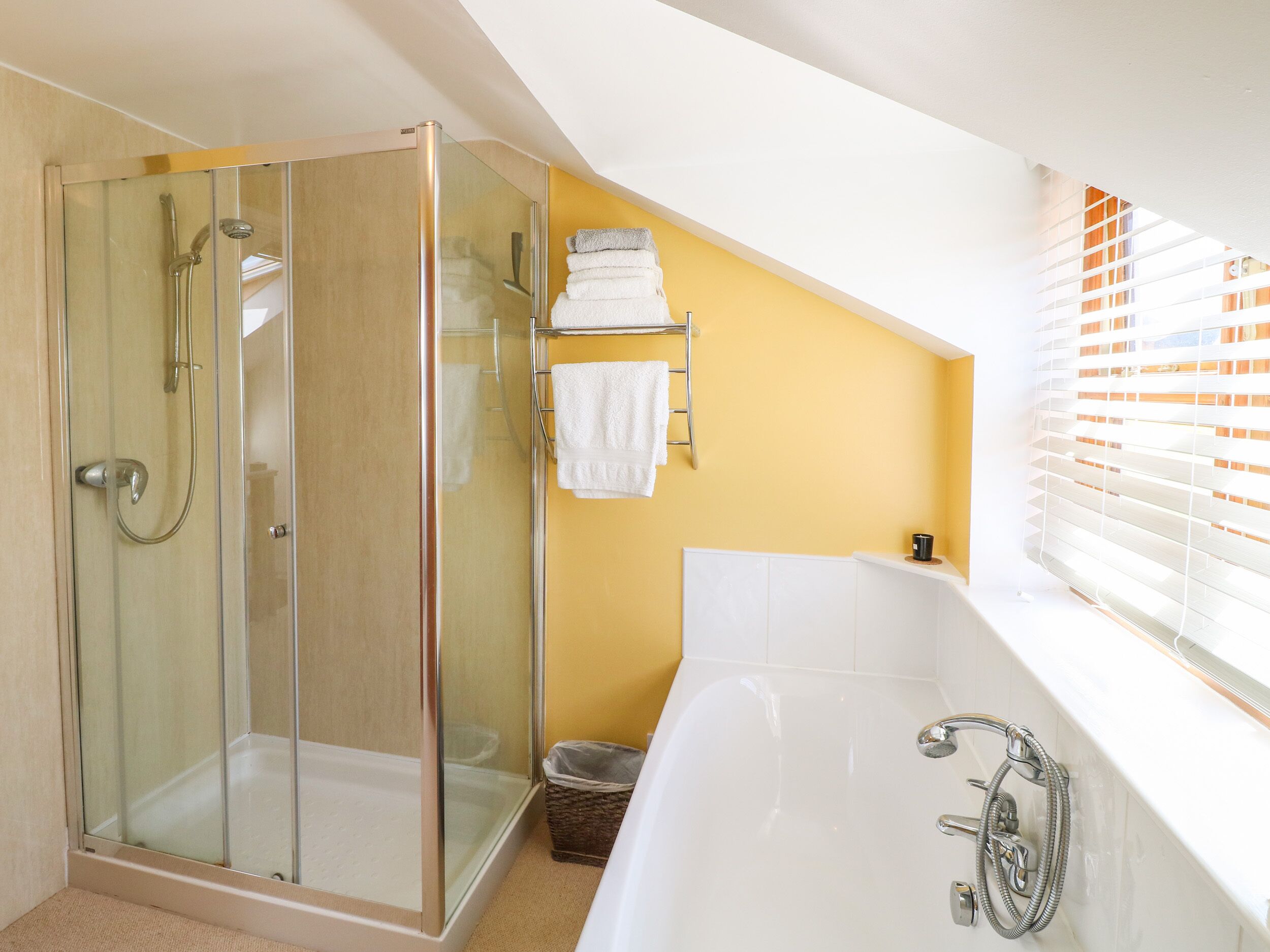 Ein modernes Badezimmer mit einer gläsernen Duschkabine, einer weißen Badewanne und einer gelben Akzentwand.