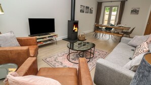 A living room with a TV, sofa, armchair, and a fireplace. - Tinners Rest (Penzance)
