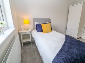 Siististi järjestetty hotellihuone, jossa on sänky, yöpöytä, lamppu ja vaatekaappi.