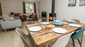 A modern living room with a sofa, armchairs, a TV, and a fireplace. - Tinners Rest (Penzance)