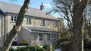 A stone house with a gabled roof, a front porch, and a stone pathway leading to the entrance. - Tinners Rest (Penzance)