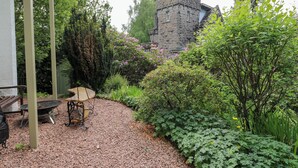 Un jardin avec une tour en pierre, un banc en bois et une table.